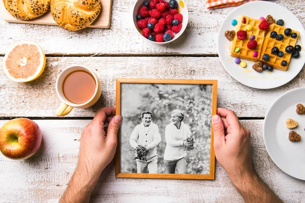 Ruce držící obraz seniorů, snídaně jídlo. Studio záběr. — Stock fotografie