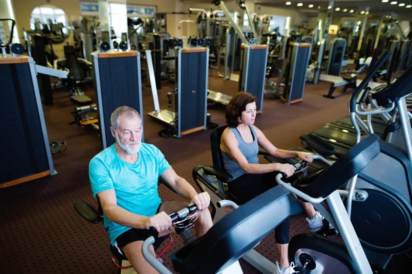 Beautiful fit senior couple in gym doing cardio work out. — Stock Photo, Image