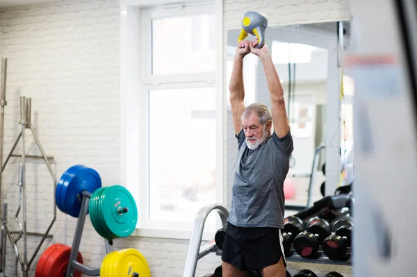 Äldre mannen i gymmet träna med kettlebells. — Stockfoto