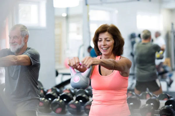 Senior paar in sportschool trainen met behulp van kettlebells. — Stockfoto