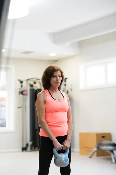 Senior Kvinna i gymmet träna med kettlebells. — Stockfoto