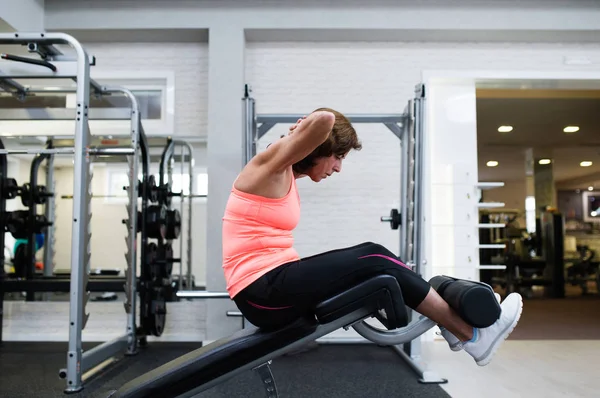 Bela ajuste sênior mulher trabalhando ela abdominais, fazendo crunches . — Fotografia de Stock