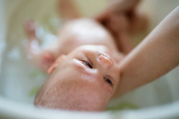 Irreconocible madre bañando a su hijo en blanco pequeño murciélago de plástico — Foto de Stock