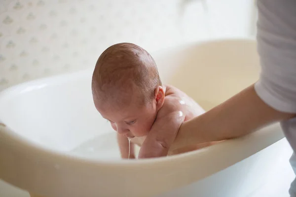 Irreconocible madre bañando a su hijo en blanco pequeño murciélago de plástico — Foto de Stock