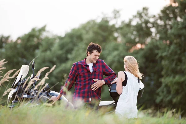 Couple in love standing at a motorbike. Green nature. — Stock Photo, Image