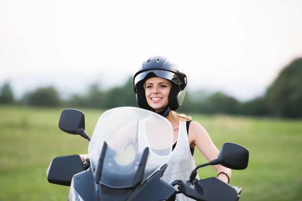 Mulher loira bonita desfrutando de um passeio de moto no campo . — Fotografia de Stock
