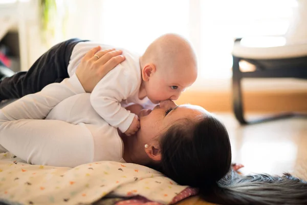그녀의 귀여운 아기 아들을 잡고 바닥에 누워 어머니 — 스톡 사진