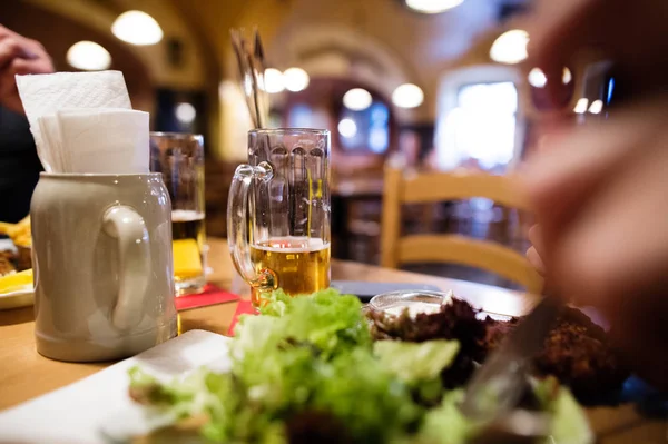 Zbliżenie z kuflem piwa i posiłek na stole. — Zdjęcie stockowe