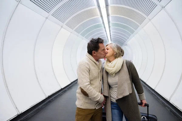 Vedoucí pár v chodbě metra tahání vozíku zavazadla. — Stock fotografie