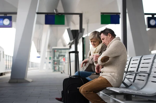 Senior couple waiting on train station, looking at watch. — Stock Photo, Image