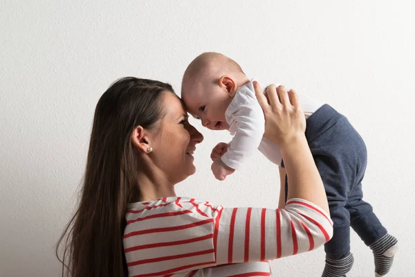 Belle mère tenant bébé fils dans ses bras. Plan studio . — Photo