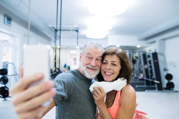Äldre par i gymmet vilar, tar selfie med smartphone — Stockfoto