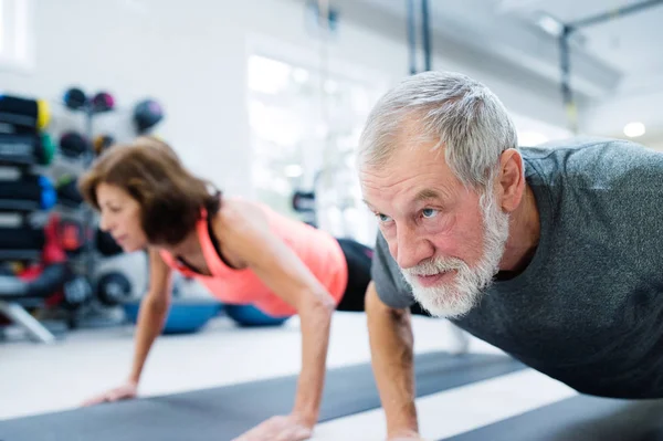 Coppia anziana in palestra che si allena, facendo flessioni — Foto Stock