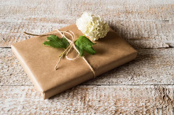 Подарок, завернутый в коричневую бумагу, лиловый цветок, положенный на него . — стоковое фото