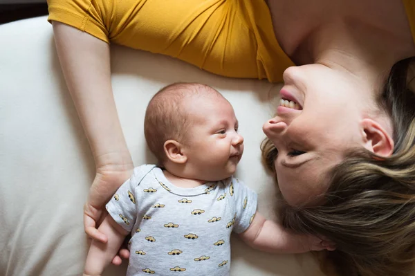 Мать с новорожденным сыном лежит на кровати — стоковое фото