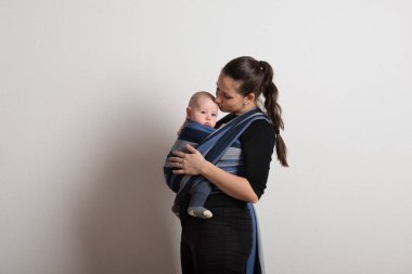 Anne oğluyla onu öperken bebek askı içinde. Stüdyo vurdu.