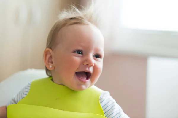 Cute little girl with bib sitting in high chair laughing — Stock Photo, Image