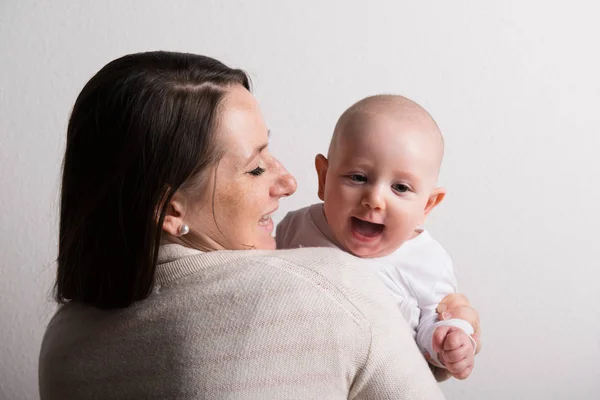 Beautiful mother holding baby son in her arms. Studio shot. — Stock Photo, Image