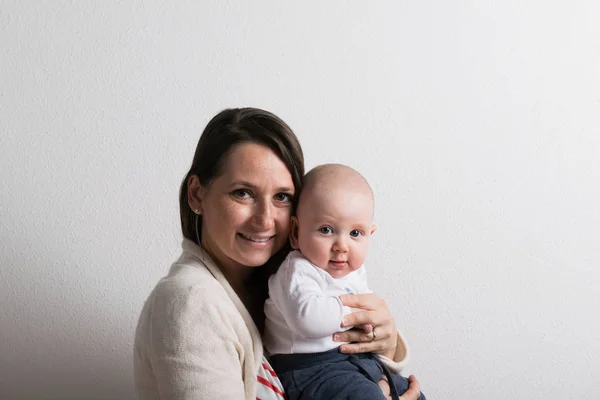 Bela mãe segurando bebê filho em seus braços. Estúdio . — Fotografia de Stock