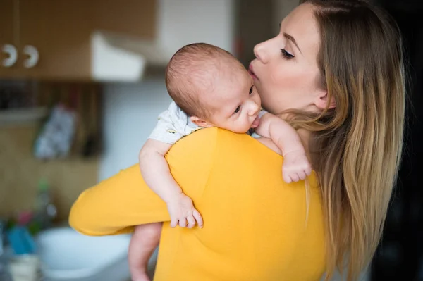 Die schöne junge Mutter hält ihren kleinen Sohn auf dem Arm — Stockfoto