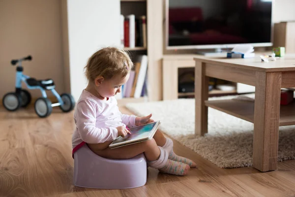 Little girl at home sitting on potty playing with tablet — Stock Photo, Image