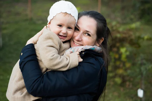 Mooie moeder die haar dochter in haar armen in de natuur. — Stockfoto