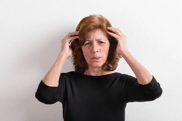 Donna anziana in t-shirt nera, tiro in studio contro muro bianco . — Foto Stock