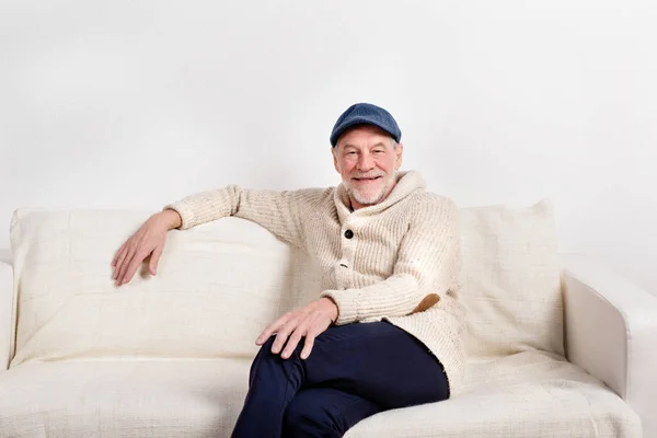 소파, 촬영 스튜디오에 앉아 베이지색 스웨터에 수석 남자. — 스톡 사진