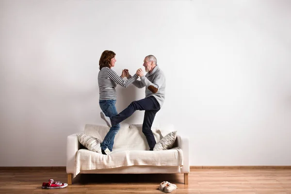 Beau couple de personnes âgées debout sur le canapé, dansant. Plan studio . — Photo