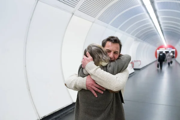 Casal sênior em roupas de inverno no corredor do metrô abraçando — Fotografia de Stock