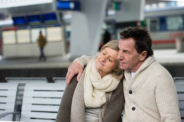 Hermosa pareja de ancianos esperando en la estación de tren, abrazos —  Fotos de Stock