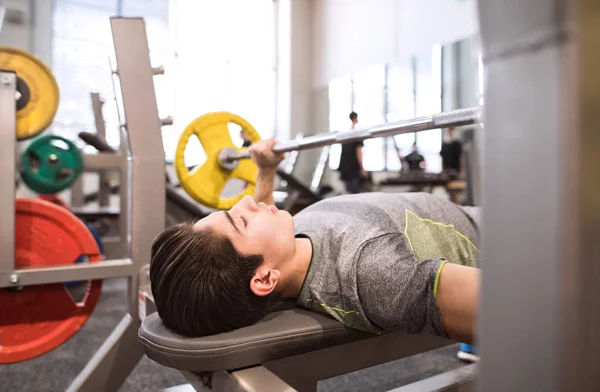 Homme hispanique dans la salle de gym travailler avec des poids, banc de pressage — Photo