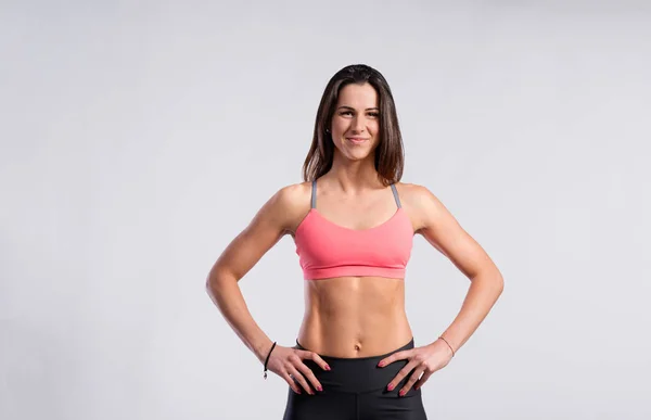 Mujer fitness en sujetador deportivo rosa y polainas, toma de estudio . — Foto de Stock