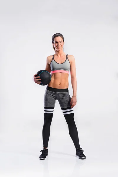 Fitness kvinna i sportkläder anläggning medicinboll, studio s — Stockfoto