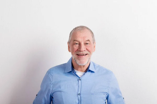 Uomo anziano in camicia azzurra sorridente, ripresa in studio . — Foto Stock