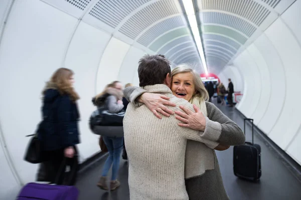 Pareja mayor en ropa de invierno en el pasillo del metro abrazándose — Foto de Stock