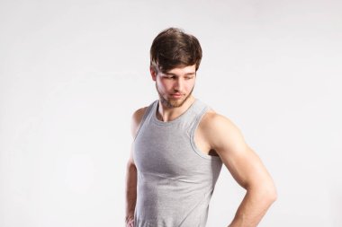 Yakışıklı fitness adam gri kolsuz bluz gömlek, stüdyo vurdu.