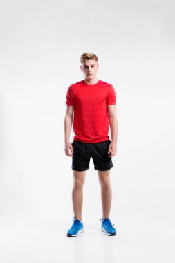 Yakışıklı fitness erkekte kırmızı t-shirt ve şort, stüdyo vurdu.