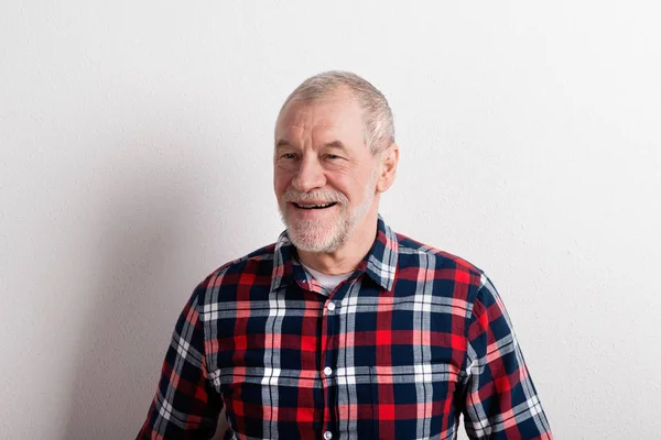 Senior man in checked shirt smiling, studio shot against white w — Stock Photo, Image