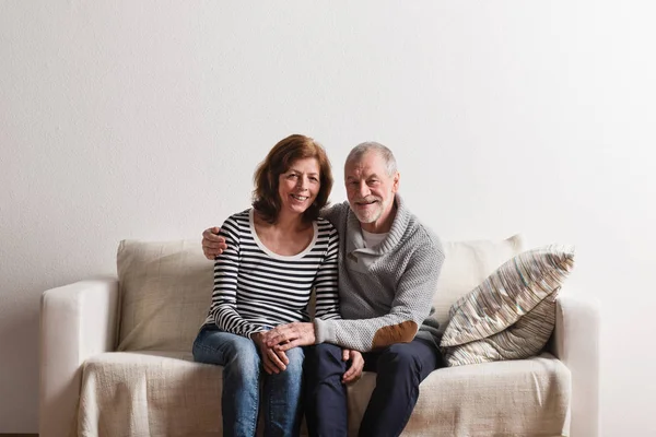 Hermosa pareja de ancianos sentados en el sofá, abrazándose. Captura de estudio . —  Fotos de Stock