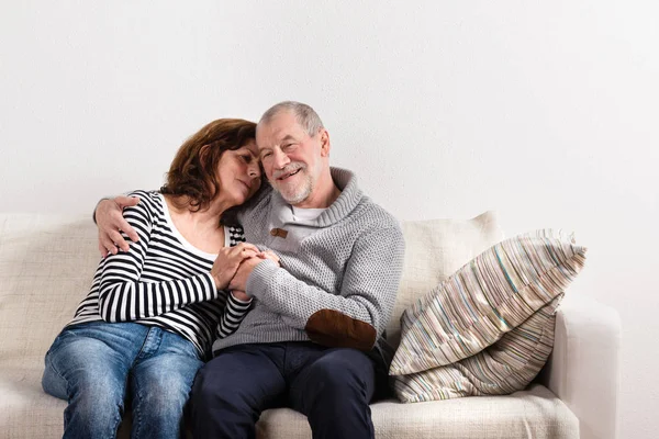 Hermosa pareja de ancianos sentados en el sofá, abrazándose. Captura de estudio . —  Fotos de Stock