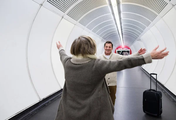 Senior para w korytarzu z metra, ciągnąc wózek na bagaż. — Zdjęcie stockowe