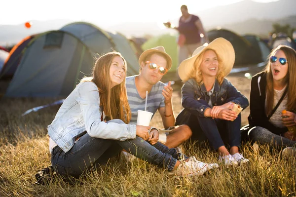 Teenagers sitting on the ground in front of tents and eating — Stock Photo, Image