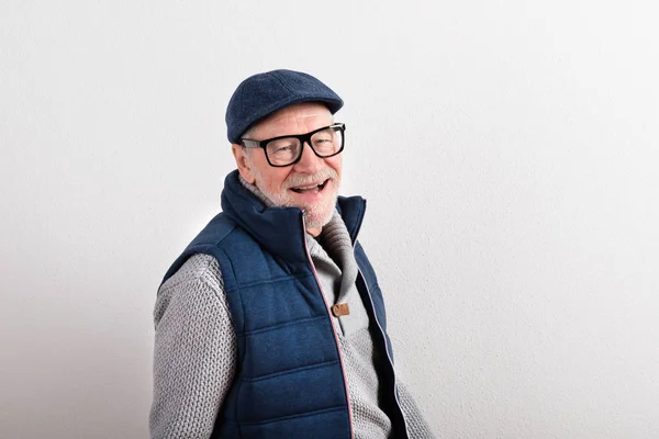 Uomo anziano in maglione, giubbotto e cappuccio, ripresa in studio . — Foto Stock