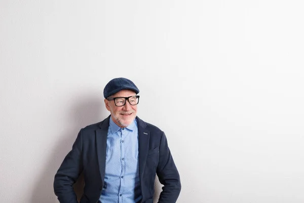 Uomo anziano in camicia blu, giacca, occhiali e cappello, ripresa in studio — Foto Stock