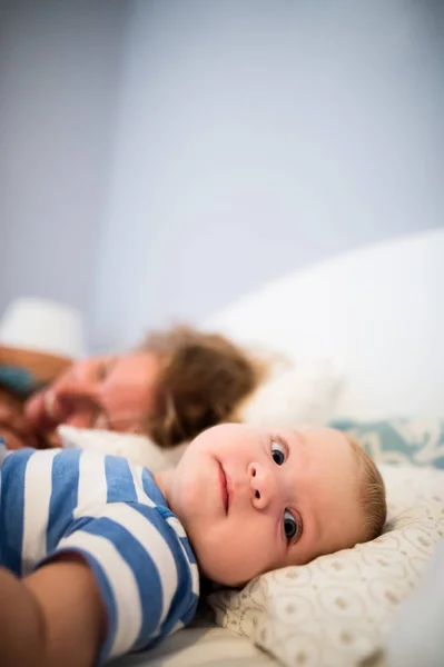 Baby boy lying on bed, held by his mother — Stock Photo, Image