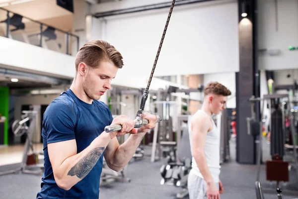 Passar ung man i gym tränar på pull-down maskin. — Stockfoto