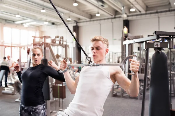 Passar ung man i gym tränar på pull-down maskin. — Stockfoto