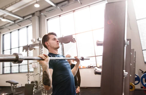 Fit mladý muž v tělocvičně cvičit, zvedání činka — Stock fotografie