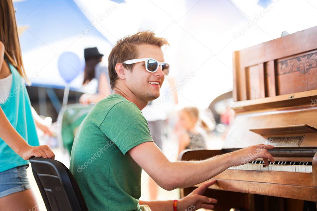 Teenage couple at summer music festival, boy plays piano